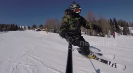 A skier with a selfie stick skiing on the tracks in mountains and taking selfies