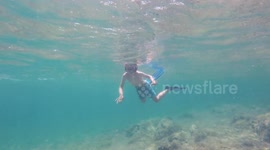Little girl with flippers, mask and snorkel swimming and diving in the sea, action camera underwater footage