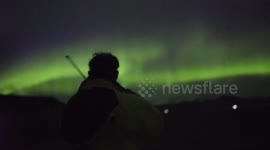 Man plays violin under incredible northern lights display