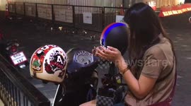 Young woman shows how she keeps pet bushbabies a box while riding motorcycle