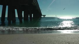 Pier with waves calmy coming onshore and birds flying around