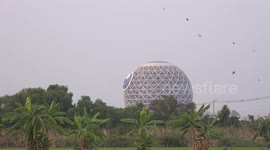 Swallows fly around a strange round temple in Thailand.