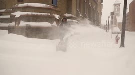 Northeast snowstorm: Man works snow blower on sidewalk in Albany