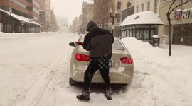 Northeast snowstorm: Man cleans off car in driving snow in downtown Albany
