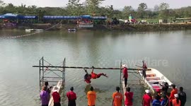 Youngsters perform Muay Thai boxing on a bamboo pole to knock each other into the water