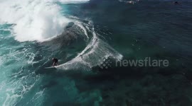 Drone footage shows a surfer catching a wave on the north shore of Hawaii