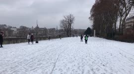 People walking on Paris Seine River’s banks during snowy weather