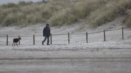Man Waling On Beach While It Snows