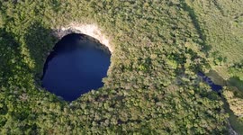 Aerial view of the Candelaria cenote, with people having fun diving from a rock