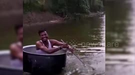 Man rows over water in cooking pot boat with spatula paddle