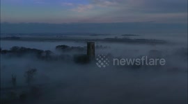 English church spire pierces thick fog in majestic scene