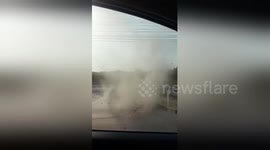 Terrified driver watches as dust devil approaches his car