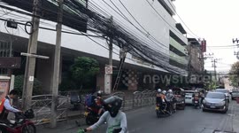 Thai workman struggles to untangle mass of overhead power cables