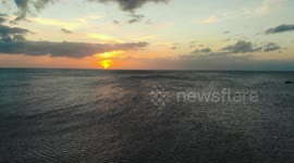 Drone camera flys over ocean during the sunset