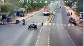 Mirclously survives a motorcycle riders as truck driver make a dramatic turn to avoid the rider in coming between the wheels in Northern India.