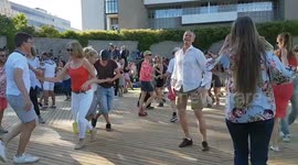 men and women dancing to Latin American music a bright summer evening outdoors