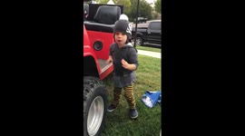 Little boy scares himself by tooting horn on golf cart