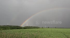 Spectacular rainbow forms over farm fields and wind power turbines in the wake of severe summer thunderstorm in Grand Bend Ontario Canada