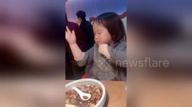 Excited girl dances after having her favourite soup in restaurant in Shanghai