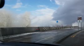 Waves crash over seafront onto passing cars in New Brighton in UK