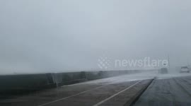Waves batter passing cars on seafront new brighton UK in gale force winds
