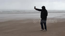 Man Measuring Strong Wind & Hailstones On Beach