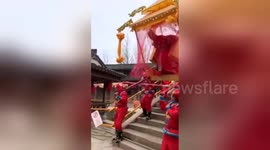 Woman tumbles out of sedan chair going downhill over bridge