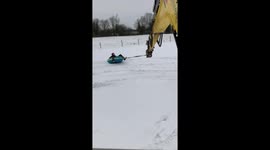 Workers take a spin in the snow with aid of excavator