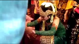 Bride in traditional Javanese wedding washes husbands feet during ceremony