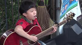 Passionate busking child stuns with rocking version of 'Let It Be' on oversized acoustic guitar