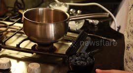 Girl puts blueberries in pot and stirs on stove