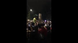 The eight-year-old boy builds the tower with small wooden sticks very high on the walking street