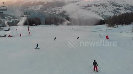snowboard on sunset alone in the middle of the mountains with snow guns on in golden hour drone shot 4K 422