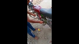 Tiny green snake keeps nipping at man trying to rescue it from motorcycle engine