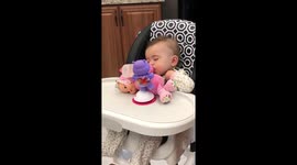 Baby struggling to make it through a Monday morning. Rubbing her own little head with her milk propped up on her toys.
