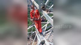 Chinese electrical workers nap on 50-metre-high transmission tower