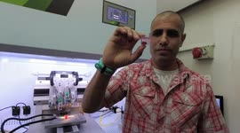 Prof. Tal Dvir of Tel Aviv university demonstrates a rabbit size 3D printed heart, while another heart is being printed in the background. The heart is made from differentiated fat cell from the heart receiver, thus eliminating host immune rejection.