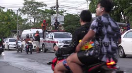 The police try to get people to stay off the centre of the road, while they celebrate Songkran festival, the guy with the speakers tells the crowd that the police are coming behind him.