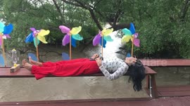 Thai lady relaxing with wind toys on bench