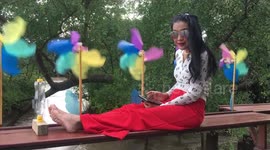 Thai lady relaxing on bench with tablet and windmills.