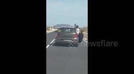Reckless passenger leans from car door to take selfie on busy road in the Canary Islands