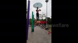 Insane workout! Fitness enthusiast bears man's weight on his waist as he performs a parallel bar exercise