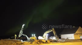 Machine workers under the Northern Lights on rural road in Norway