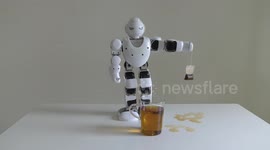 A domestic android humanoid robot helps making tea even stronger for his master by steeping a tea bag in boiling water in a glass cup
