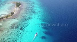 Boat sailing past tropical island.