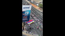 Anti-maduro protesters unfurl flag as they gather at highway in Caracas