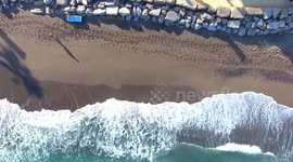 aerial view of one person walking on beach with waves crashing, drone footage