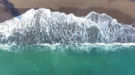 Aerial view of waves crashing down on sandy beach in marbella.