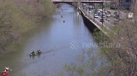 People in canoes paddles down the Don River alongside the highway on beautiful warm sunny spring day in Toronto Canada