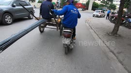 Extraordinary moment! A man driving a motorbike uses one leg to push a long and heavy block of steel moving on the road